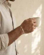 بنگل نقره لاین در دست مرد، فضا با دیوار کرم و لیوان
